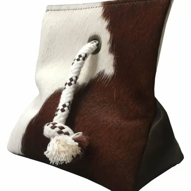 Brown and white cowhide doorstop with a ropeon a white background
